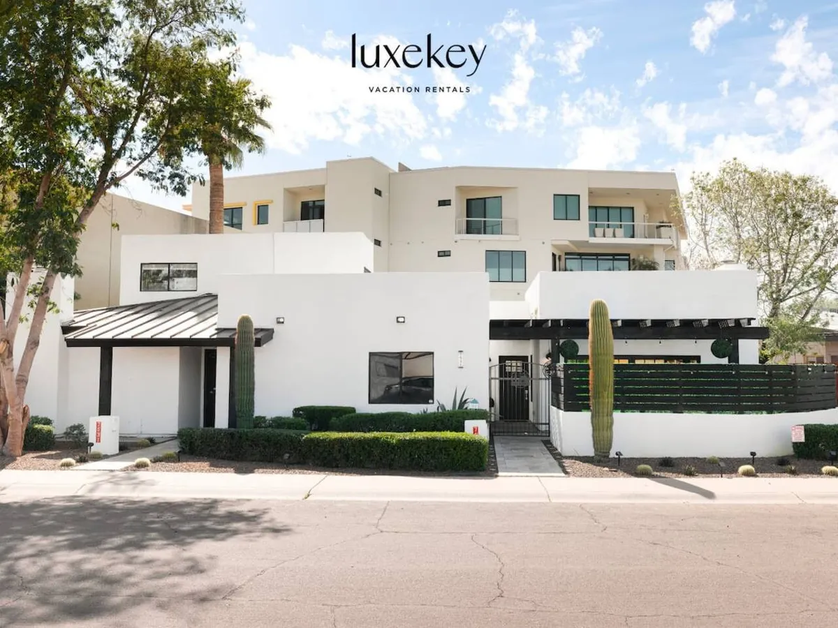 A contemporary exterior view highlighting modern architecture framed by lush greenery and desert cacti. The clean lines and inviting design reflect an upscale, vibrant environment with space for community gatherings. The scene hints at easy access to local attractions and the lively surroundings of Old Town Scottsdale.
