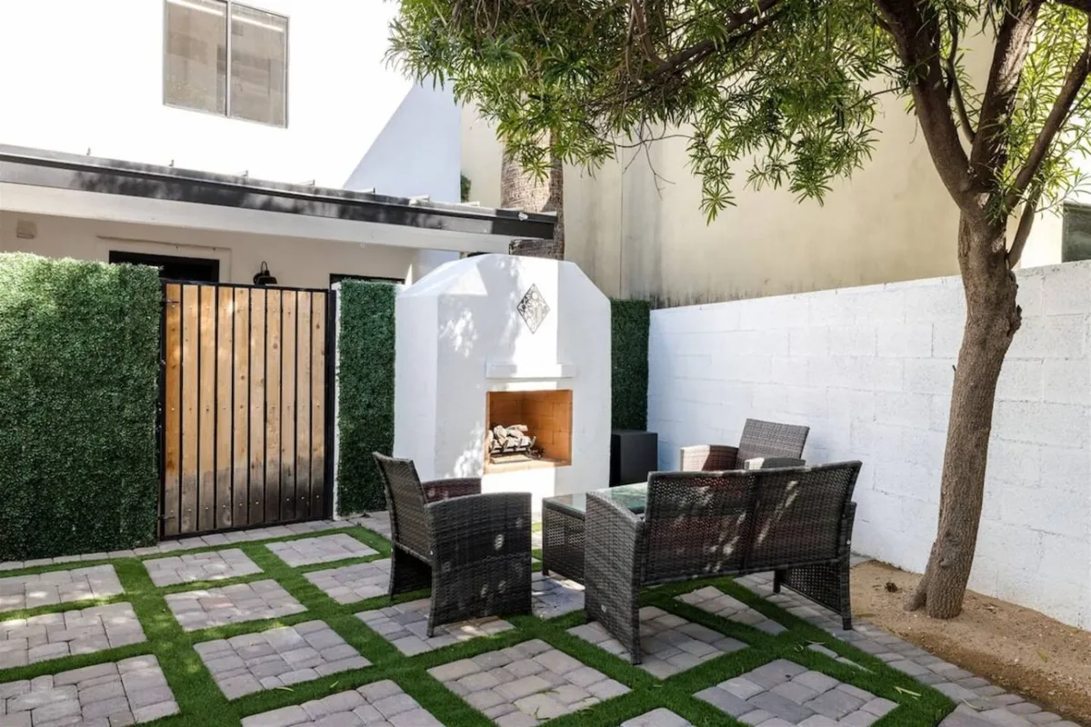 The hero image showcases a beautifully paved stone patio with plush seating arranged around a glowing outdoor fireplace, bordered by a decorative hedge. The cozy ambiance invites relaxation and gathering, perfect for evening conversations or memorable outdoor celebrations under the Arizona sky.