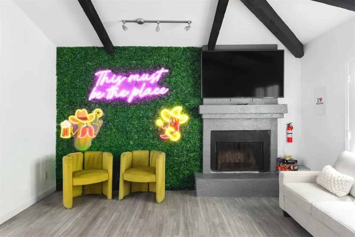 A lounge space highlighted by a neon sign and a lush green accent wall. Yellow chairs and a contemporary fireplace form a social hub, ideal for relaxed conversations or celebratory moments. The setting feels joyful and designed for memorable interactions.