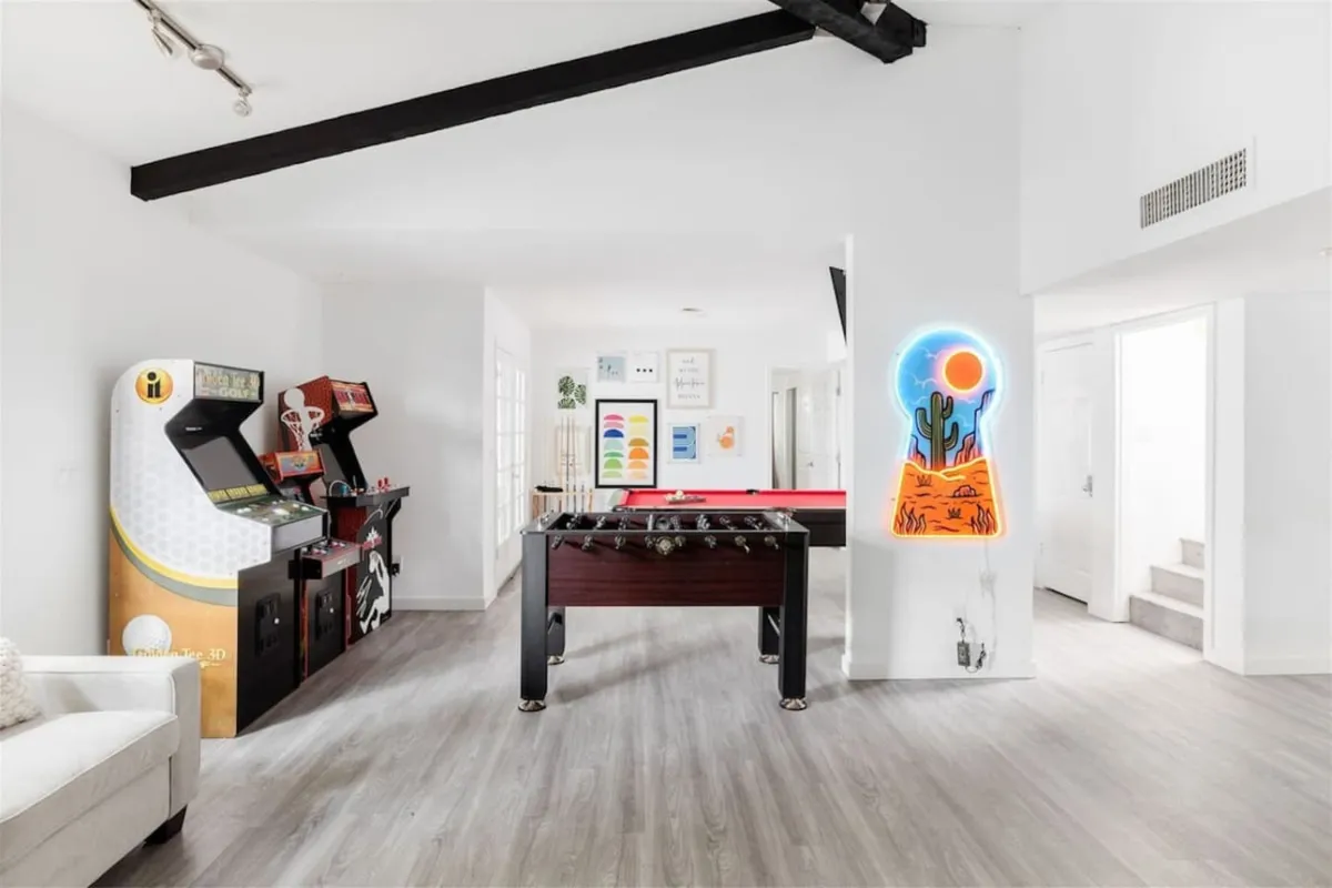 This image showcases a lively game room featuring arcade machines, a foosball table, and colorful neon wall art. The setup exudes a fun, energetic atmosphere, ideal for both group gaming sessions and casual hangouts. The bright colors and vibrant decor reinforce the playful mood described in the section.